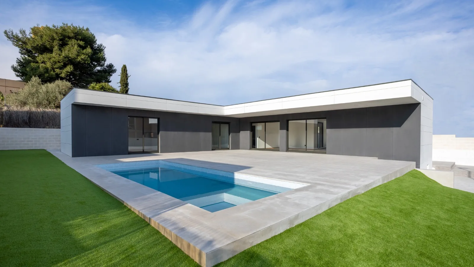 Homi II: volumen en L de porcelánico grafito abrazando la piscina de gres